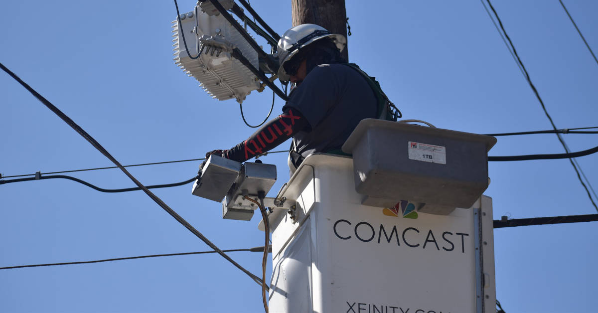 A Comcast technician works on a utility line in an undated photograph.