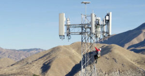 An engineer climbs a wireless network tower.
