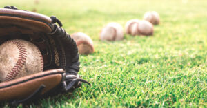 A baseball glove with baseballs nearby.