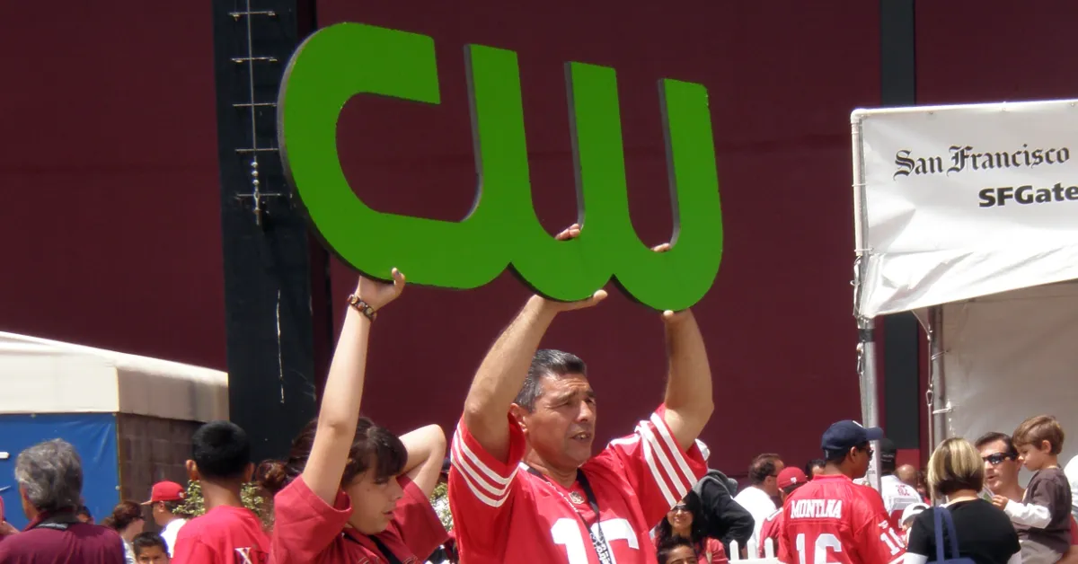 Fans of the San Francisco 49ers football team hold a sign with the logo of the CW Network during an event at Candlestick Park in 2009.